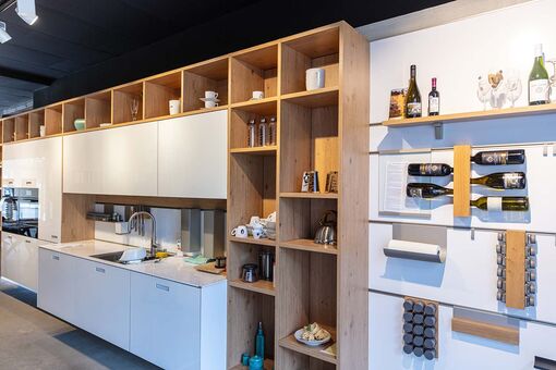 Moderne weiße Küchenwand mit Ober- und Unterschränken und offenem Holzregal sowie praktische Wandleisten